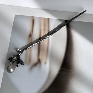 Detailed view of dark metal hair pin with handcrafted texture and pearl flower bud