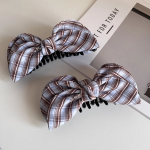 Close-up of purple plaid bow banana clip with elegant metal emblem and neat stitching