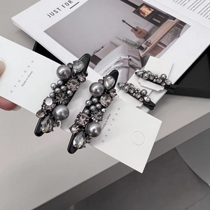 Detail of luxury hair clip set featuring dark grey pearls and sparkling crystals on card