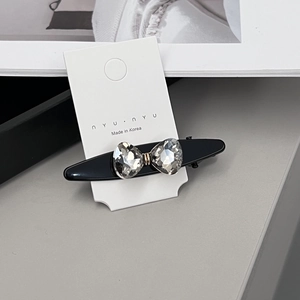 Détail d'une barrette noire en forme de nœud avec des cœurs en strass de cristal