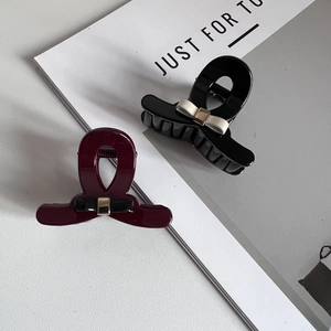 Close-up of glossy resin hair claws with contrast bows and gold metallic buckles