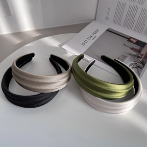 Detailed close-up of wide padded headbands in satin fabric with pleated texture accents