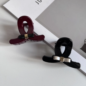 Detail of elegant black and wine red bow hair claws with glossy resin finish and gold accents