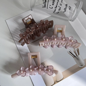 Close-up of floral hair claws with pearls in dark brown, light pink, and cream white colors