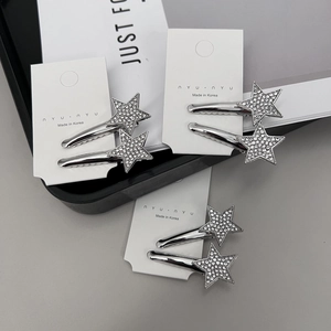 Détail de barrettes étoiles argentées avec strass incrustés sur une carte de présentation