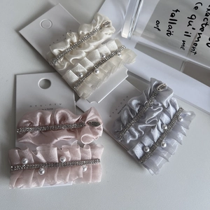 Detailed macro view of satin fabric hair clips with small rhinestones and pearls