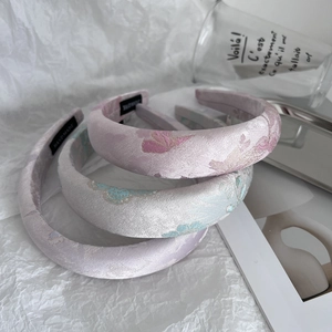 Close-up of handmade embroidered satin headbands with floral patterns in soft pastel tones