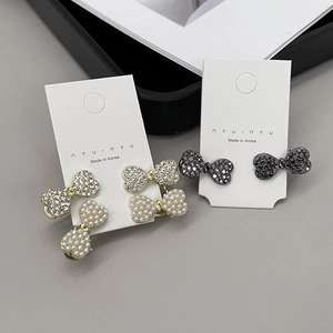 Fermi per capelli a fiocco con perle e strass su una carta di presentazione