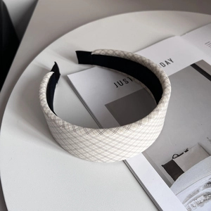 Detailed view of a wide beige checkered fabric headband with non-slip inner lining