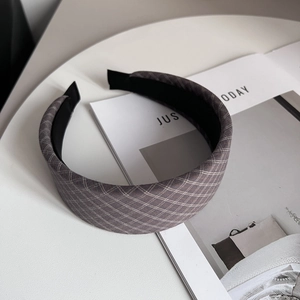 Close-up of a wide padded headband featuring grey plaid fabric texture and non-slip lining