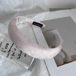 Detailed view of handmade pink satin headband on white fabric with French glass decor