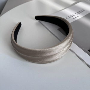 Close-up of champagne fabric headband showing delicate pleated texture and glossy finish