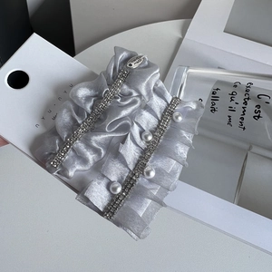 Close-up of pearl and rhinestone hair clips with pleated silver grey fabric texture