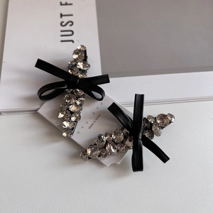 Elegant rhinestone bow hair clip set with black leather texture and crystals on white background