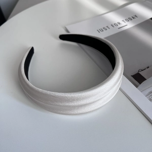 Detail of white padded headband with faux leather texture and elegant pleated design