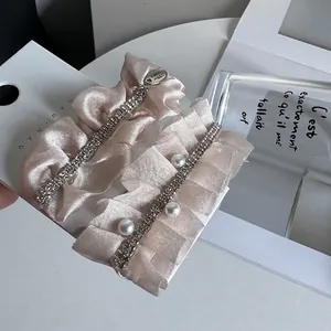 Detailed close-up of pink pleated fabric hair clips with pearls and shiny rhinestones