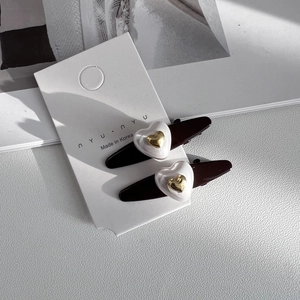 Détail de deux barrettes marron foncé avec cœur 3D blanc et motif doré en relief