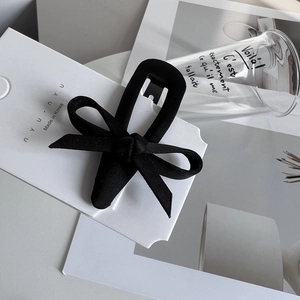 Detail of elegant black fabric bow hair clip on a minimalist brand display card