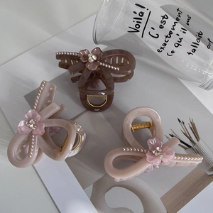 Detail of three pearl-beaded acrylic hair claws in coffee, beige, and pink bow designs