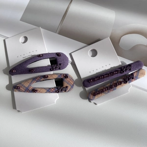 Detailed macro shot of four purple plaid fabric hair clips with rhinestone Kitty ornaments