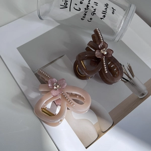 Detail of elegant acrylic bow hair clips with pearls and rhinestones in soft pink and brown