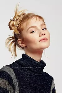 Détail d'une élégante pince à cheveux dorée en métal portée sur un chignon de femme