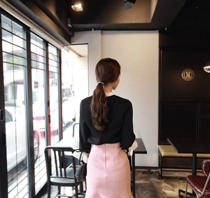 Detail of the pink slim-fit midi skirt paired with black chiffon shirt and white ruffles