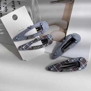 Detailed macro shot of four blue plaid hair clips with rhinestones on a display card
