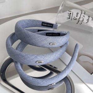 Three light blue plaid headbands with metal ornaments in a stylish metal tray