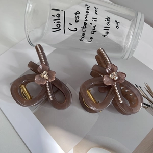 Detailed view of brown resin hair claw clips with matte flowers and pearl accents
