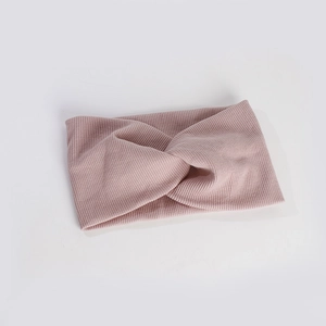 Détail du bandeau en maille côtelée rose poudré avec un élégant nœud torsadé