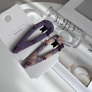 Close-up of purple fabric hair clips with rhinestones and elegant gold lettering detail