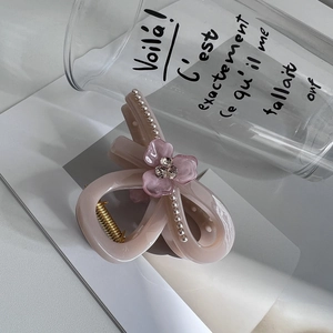 Close-up of dusty pink acrylic hair claw with rhinestone flower and gold metal spring