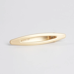 Macro detail of matte gold alloy hollow oval hair clip with secure spring duckbill mechanism