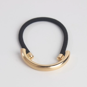 Minimalist gold metal semi-circle ponytail holder with black elastic hair tie on white background