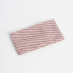 Detailed texture of dusty pink knitted headband with vertical ribbed pattern and elastic fabric