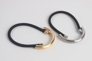 Close-up of minimalist gold and silver half-round metal buckles on black elastic hair ties