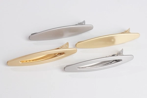 Detail view of gold and silver alloy duckbill hair clips in solid and hollow oval designs