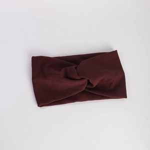 Texture détaillée du bandeau en tricot côtelé bordeaux avec design à nœud croisé