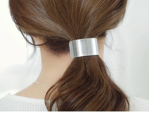 Detail showing a silver brushed metal arched hair clip securing a ponytail in hair