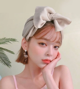 Dettaglio di una fascia in maglia a coste beige con un grande fiocco su una modella