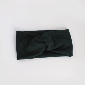 Détail d'un bandeau en tricot vert foncé avec un nœud torsadé et une texture côtelée