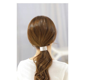 Detail of silver brushed metal spring clip on low ponytail with minimalist texture