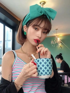 Detail showing mint green knitted oversized bow headband with matching earrings in a cafe