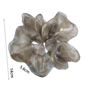 Detail view of champagne gold organza scrunchie with 14cm diameter and shiny texture
