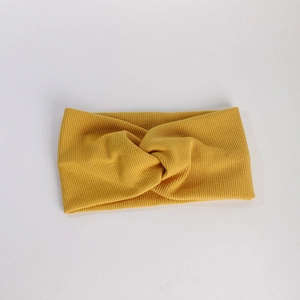 Détail du bandeau en tricot côtelé jaune gingembre avec nœud central sur fond blanc