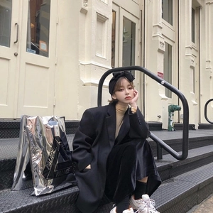 Street style shot of a woman wearing a wide black knitted bow headband with an autumn outfit