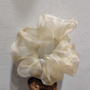 Elegant champagne organza scrunchie with shimmer texture on a wooden stand