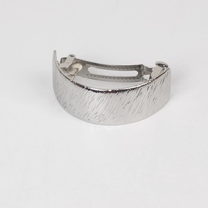 Macro view of silver brushed metal hair clip showing spring mechanism and texture