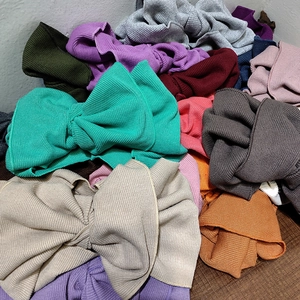 Dettaglio di fasce per capelli in maglia a coste multicolore con grandi fiocchi